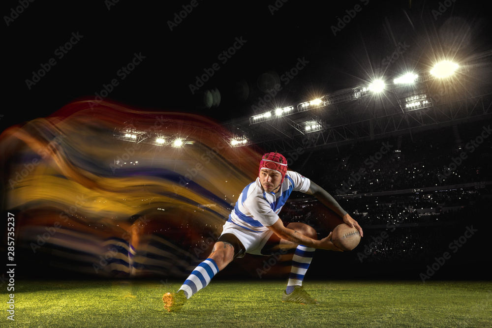 Ready for winning. One caucasian man playing rugby on the stadium in mixed light. Fit young male player in motion or action during sport game. Concept of movement, sport, healthy lifestyle.