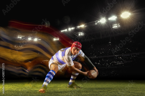 Ready for winning. One caucasian man playing rugby on the stadium in mixed light. Fit young male player in motion or action during sport game. Concept of movement, sport, healthy lifestyle. © master1305