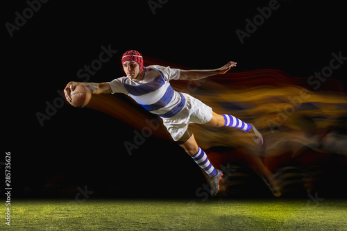 Ready to fly for win. One caucasian man playing rugby on the stadium in mixed light. Fit young male player in motion or action during sport game. Concept of movement, sport, healthy lifestyle. © master1305