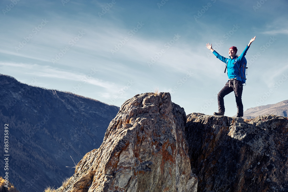 Fototapeta premium Hiker woman with backpack on rock of a mountain and enjoying sunrise. Travel Lifestyle success concept adventure active vacations outdoor mountaineering sport