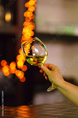 Hand sommelier holding glass of white wine. Wine-tasting. White wine concept. Wine tour. Vertical, warm toning. Free space for text.