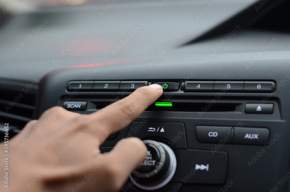 hand turn on the radio in the car.Hand driver touching the screen and turning on car radio system,Button on dashboard in car panel hand turn on the radio in the car.Hand driver touching the screen and turning on car radio system,Button on dashboard in car panel