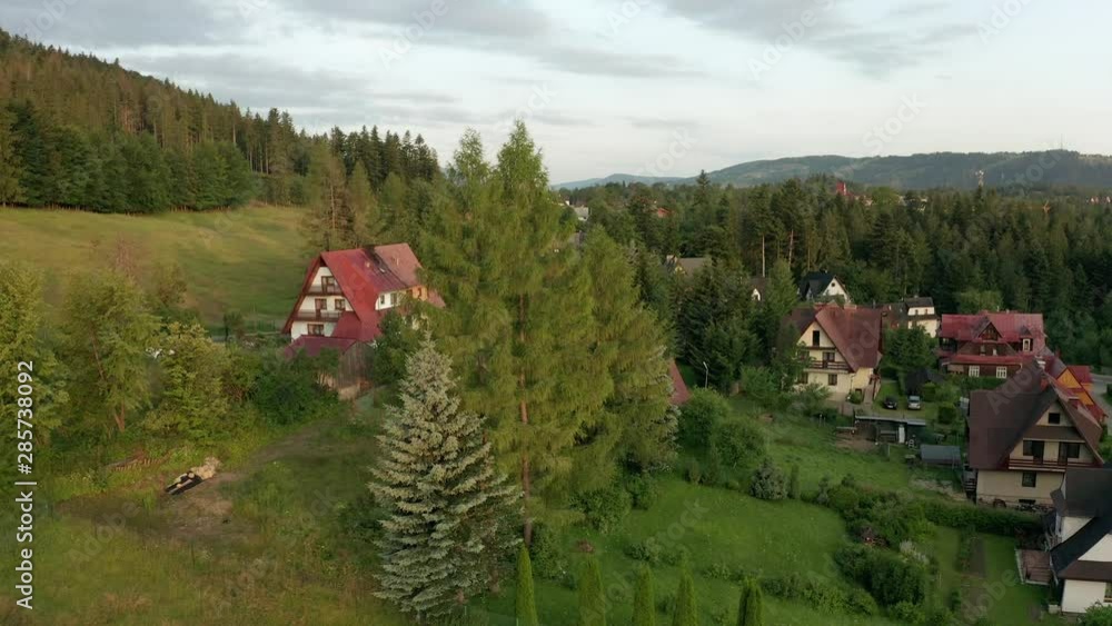 Drone shot at a village in the mountains sunrise. Cottage houses in the tourist city of Zakopane in Poland. 4K
