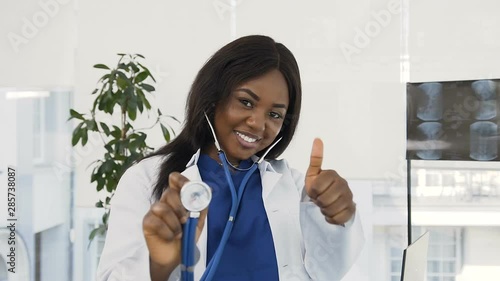 Portrait of confident female medical doctor in white coat and with stethoscope in the hand smiling to the camera in the hospital. photo