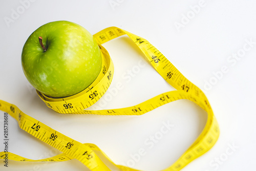 Picture of an apple with greengreen apple with waist  measure tape. Diet, clean food, weight loss concept. photo