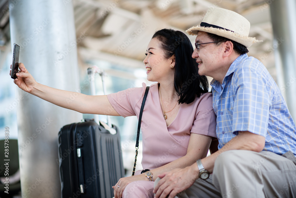 Elderly couple using a cell phone self-portrait while traveling abroad happily.