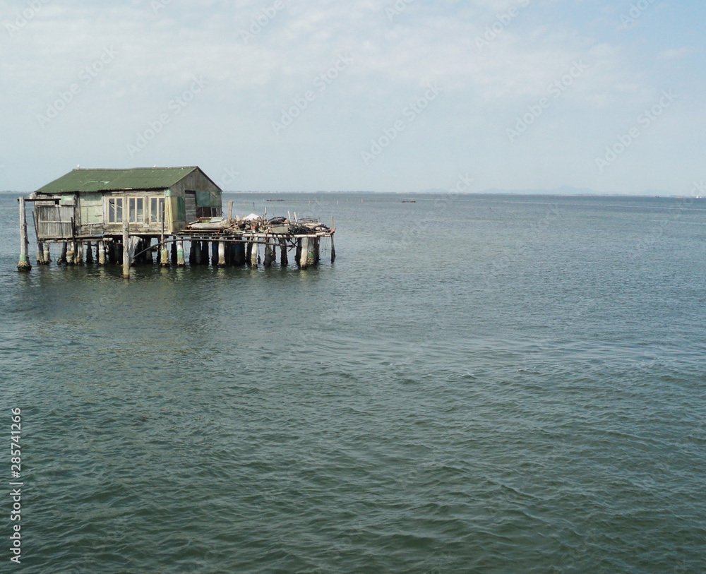 An old wooden house stands on the water. Blue sea, waves. An old wooden house stands on the water. Blue sea, waves.