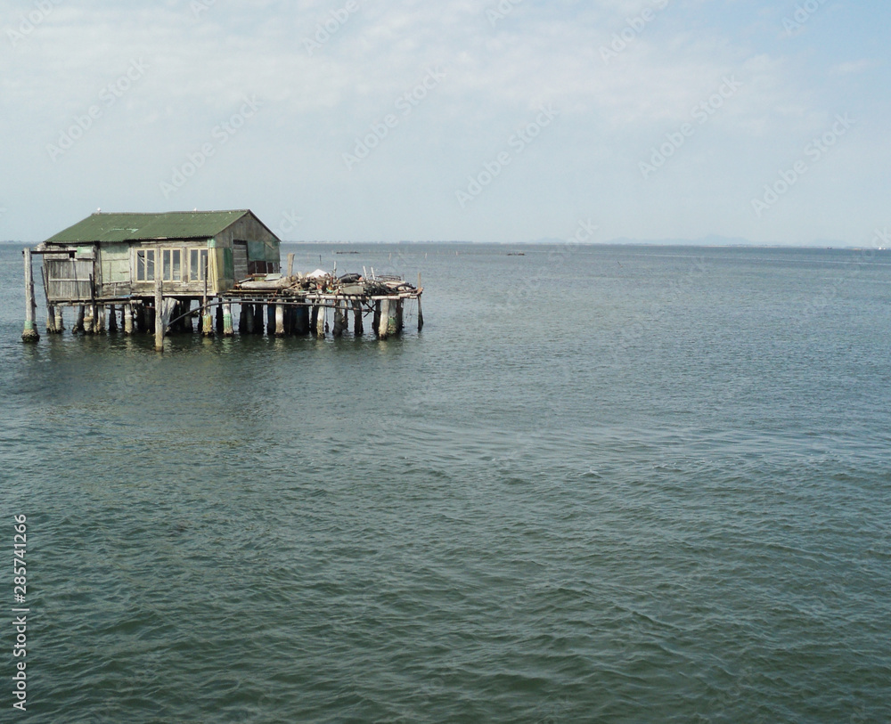 An old wooden house stands on the water. Blue sea, waves.