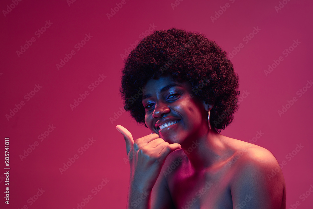 Summer's sunset. Portrait of female fashion model in neon light on pink gradient studio background. Beautiful african woman with trendy make-up and well-kept skin. Vivid style, beauty concept. Summer's sunset. Portrait of female fashion model in neon light on pink gradient studio background. Beautiful african woman with trendy make-up and well-kept skin. Vivid style, beauty concept.