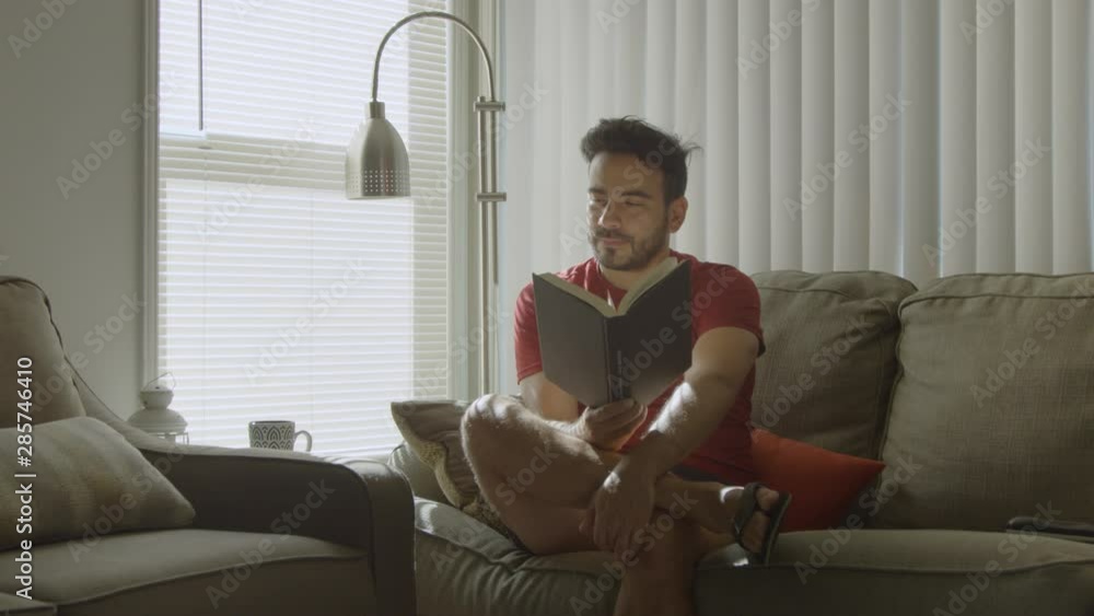 Slow motion of man holding a book as he looks up thinking Slow motion of man holding a book as he looks up thinking