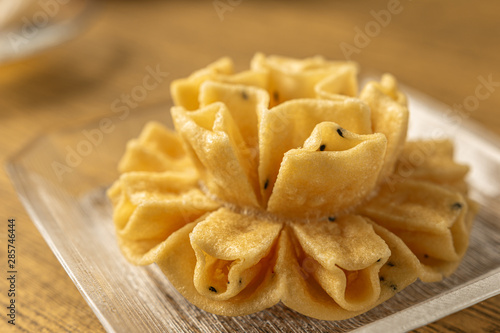 Crispy lotus blossom cookie or Dok Jog on the wooden table background of Thai desserts. Thai traditional snack.