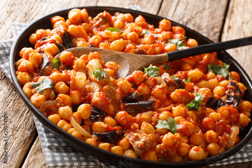 Spicy Middle Eastern chickpea food with eggplant, tomatoes, onions, herbs and spices closeup on a plate. horizontal photo