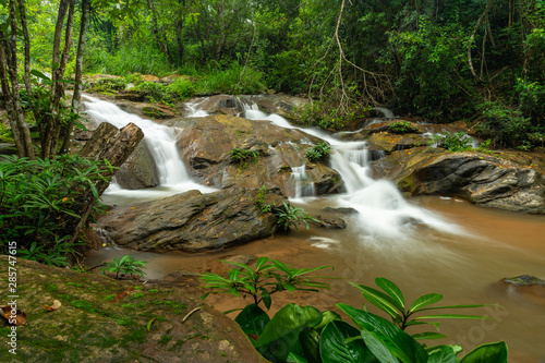 Water cascading from layer of large rocks of Mae Sa Noi waterfall with misty water effect