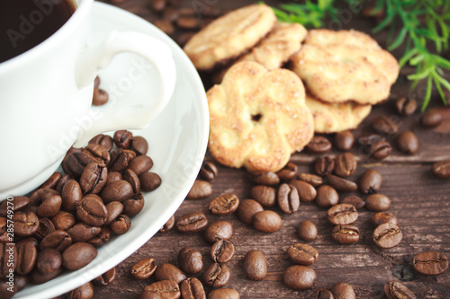 Cup of coffee, coffee beans and cookies on a dark wooden table