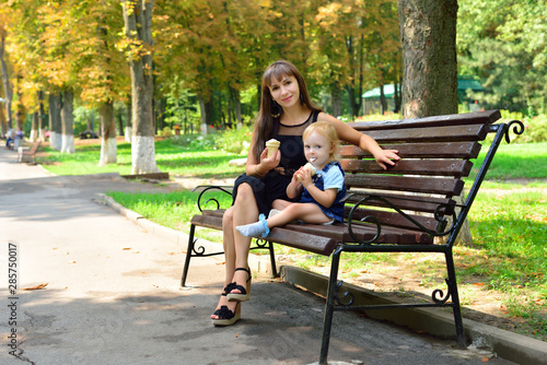 Mom and daughter eat ice cream on the bench
