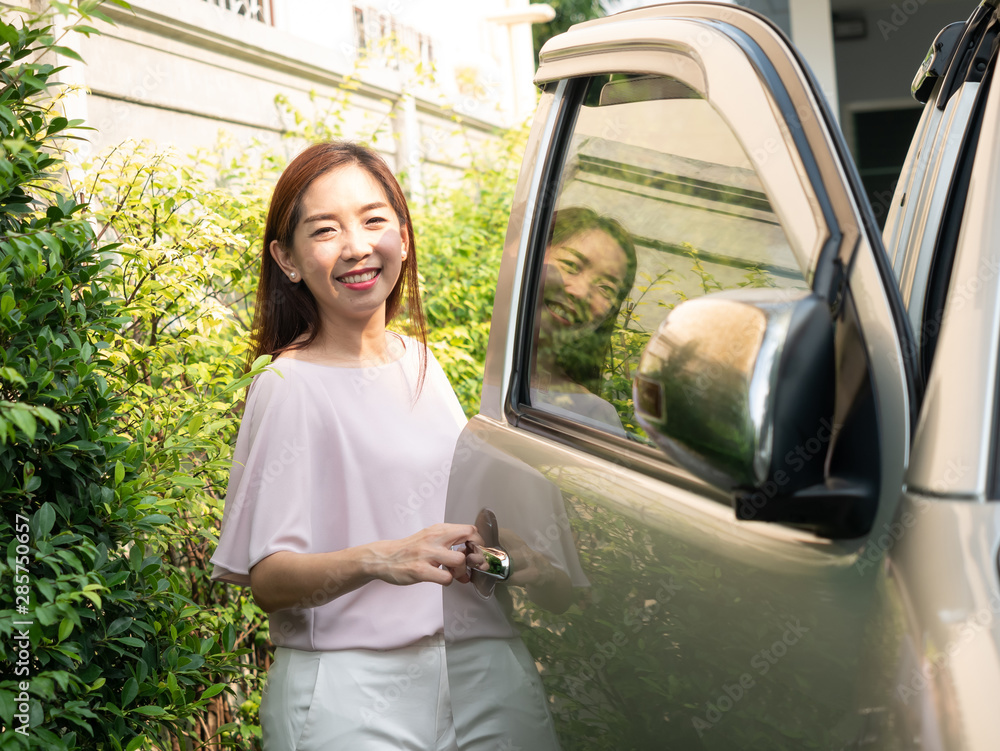 Asian woman standing beside a car.