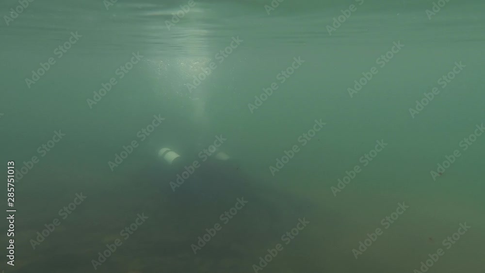 scuba divers explore the rocky bottom in shallow water. young diver training. slow motion. dive into a mountain lake scuba divers explore the rocky bottom in shallow water. young diver training. slow motion. dive into a mountain lake