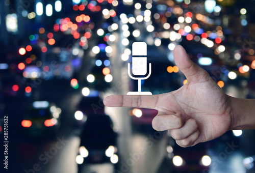 Microphone flat icon on finger over blur colorful night light traffic jam road with cars in city, Business communication concept