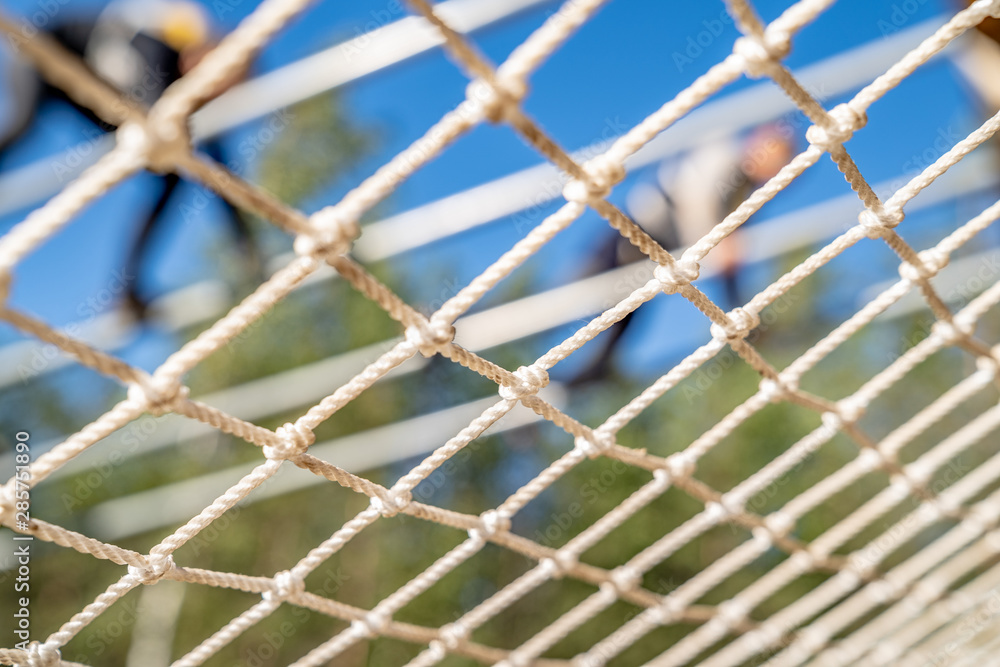 White mesh close-up. A blurry person overcomes an obstacle In the background. Sport event. Clear blue sky White mesh close-up. A blurry person overcomes an obstacle In the background. Sport event. Clear blue sky