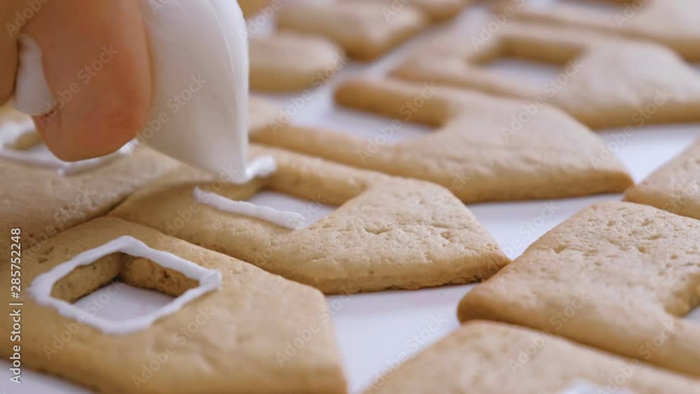 Woman's hands decorate with sugar sweet cookies for gingerbread houses. Cooking homemade gingerbread house Woman's hands decorate with sugar sweet cookies for gingerbread houses. Cooking homemade gingerbread house