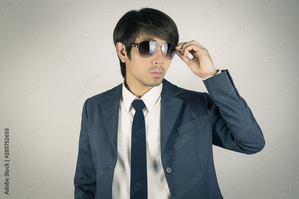 Young Asian Portrait Businessman Touch Sunglasses and Look Above in Vintage Tone Young Asian Portrait Businessman Touch Sunglasses and Look Above in Vintage Tone
