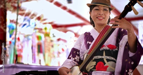 Japanese woman in traditional kimono dress playing shamisen at cultural festival, 4K