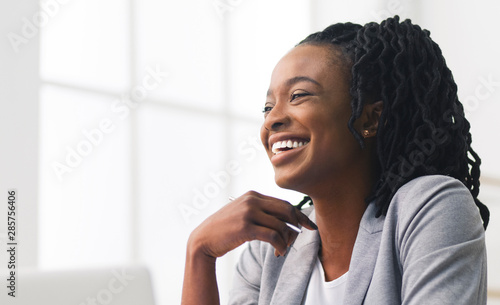 Portrait Of Black Office Girl Laughing Sitting Against Window photo