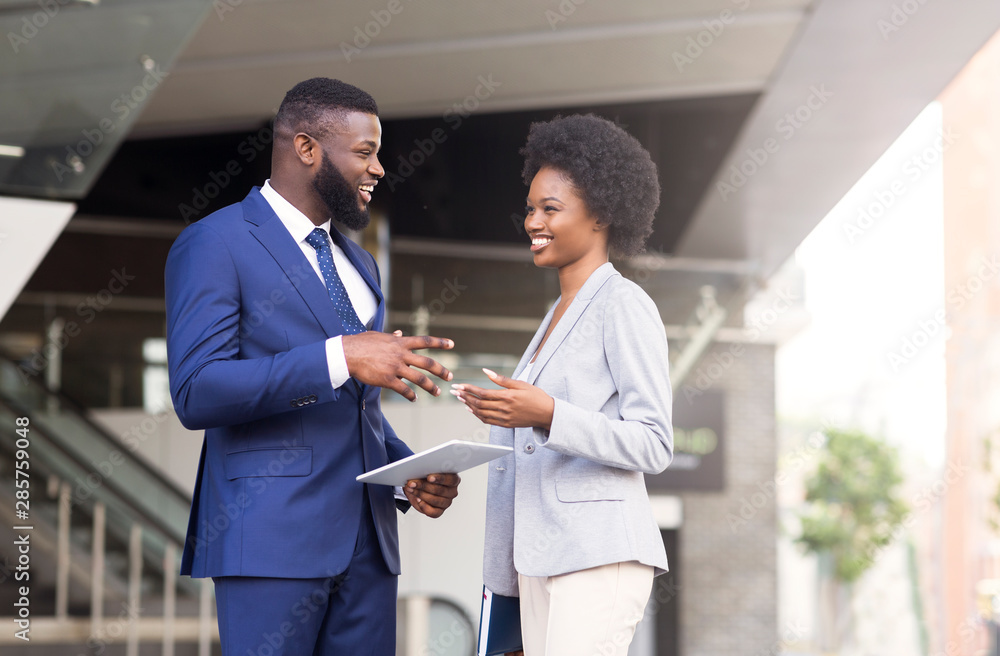 Fototapeta premium Handsome black man telling joke to his female colleague