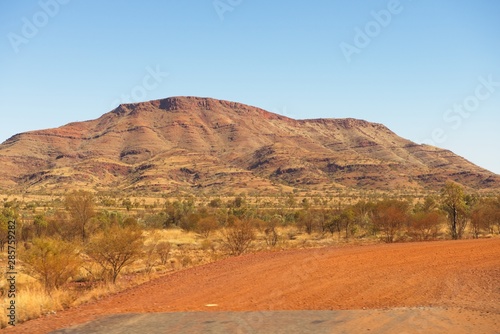 Panoramic view of mountain and bush vegetation of Pilbara outback landscape in Western Australia  with sunny blue sky as background.