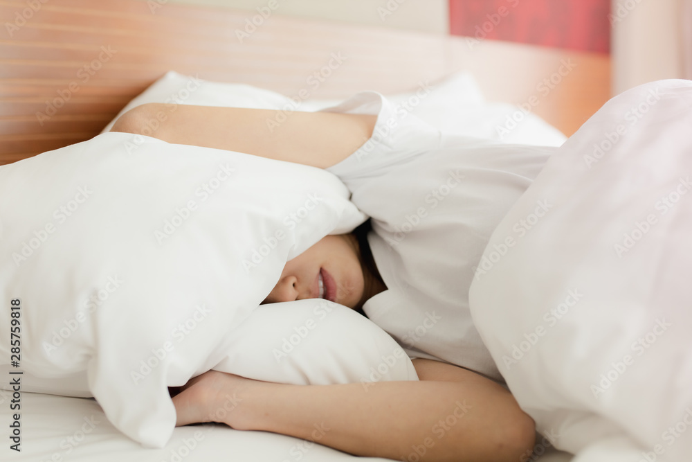 Woman stretching in bed after waking up, back view. Woman sitting near the big white window while stretching on bed after waking up with sunrise at morning, back view. Woman stretching in bed after waking up, back view. Woman sitting near the big white window while stretching on bed after waking up with sunrise at morning, back view.