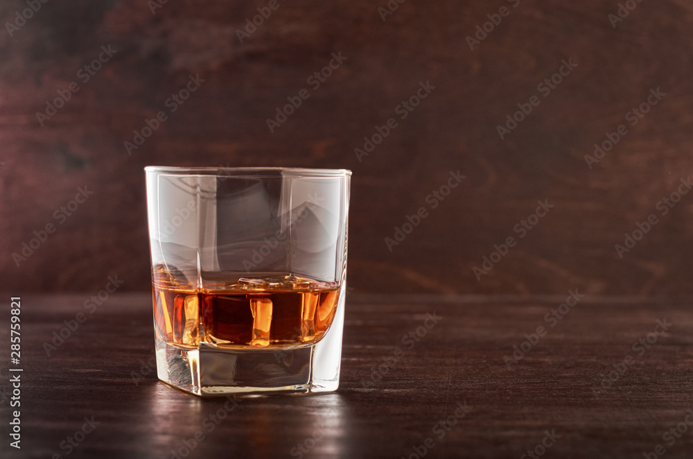 A full glass of whisky with ice on a wooden table A full glass of whisky with ice on a wooden table