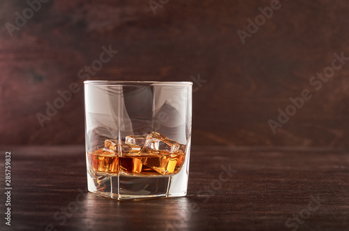 Glass of whiskey with ice on a wooden table