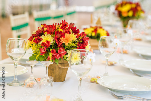 Wedding table set up decoration made of red and yellow fresh flowers. Rustic/ garden wedding decoration