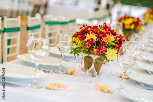 Wedding table set up decoration made of red and yellow fresh flowers. Rustic  garden wedding decoration