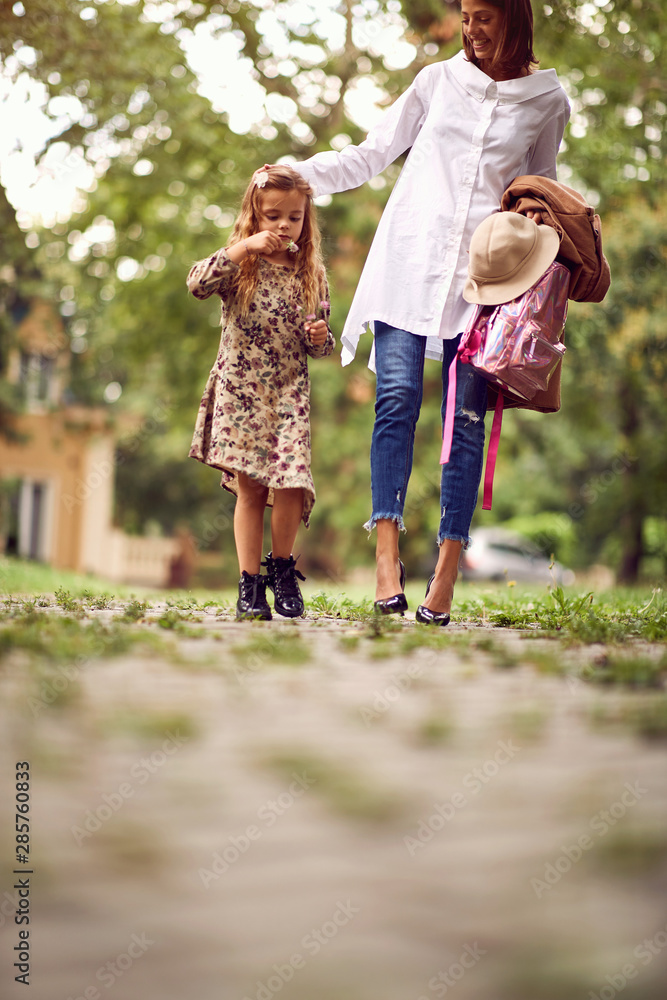Fototapeta premium Mother and school girl going home from school.