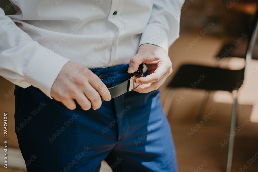 Man Putting On A Belt. Brick wall background Man Putting On A Belt. Brick wall background