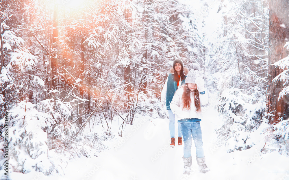 Young family for a walk. Mom and daughter are walking in a winter park. Young family for a walk. Mom and daughter are walking in a winter park.