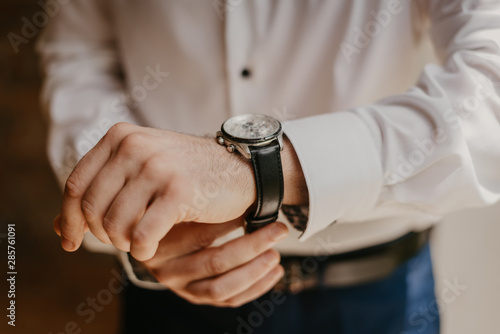 Man  with a white shirt putting on a watch. Preparation. Formal wear. 