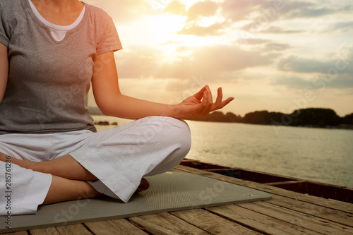 Woman in yoga pose on dock, concept