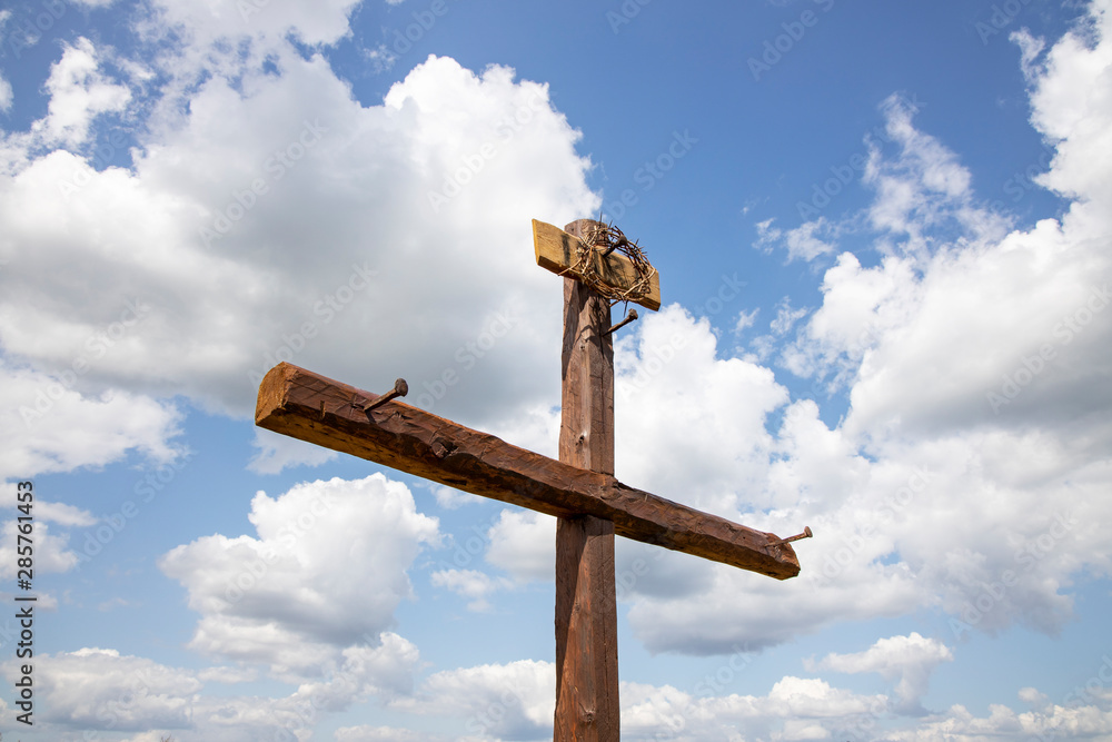 The Cross with bright sun and clouds in the background. Wood cross on blue sky. Christian background. The Cross with bright sun and clouds in the background. Wood cross on blue sky. Christian background.