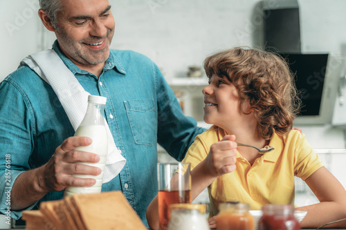 Mature father with milk making breakfast for son