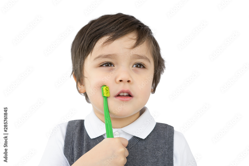 Toddler boy holding toothbrush and looking out isolated on white background, Kid boy in school uniform learning how to brush his teeth at school,Child development or Dental hygiene concept Toddler boy holding toothbrush and looking out isolated on white background, Kid boy in school uniform learning how to brush his teeth at school,Child development or Dental hygiene concept