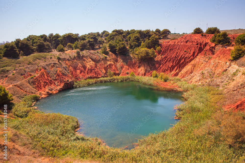 The lake in a old bauxite's red soils quarry cave in Apulia, Otranto, Salento, Italy. The digging was filled with natural waters.