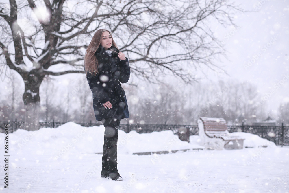 Girl in a winter park in snowfall Girl in a winter park in snowfall