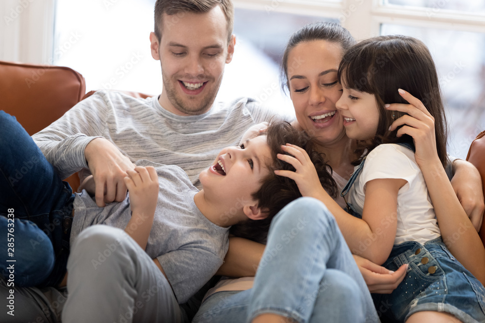 Happy mum dad having fun with kids tickling on sofa Happy mum dad having fun with kids tickling on sofa