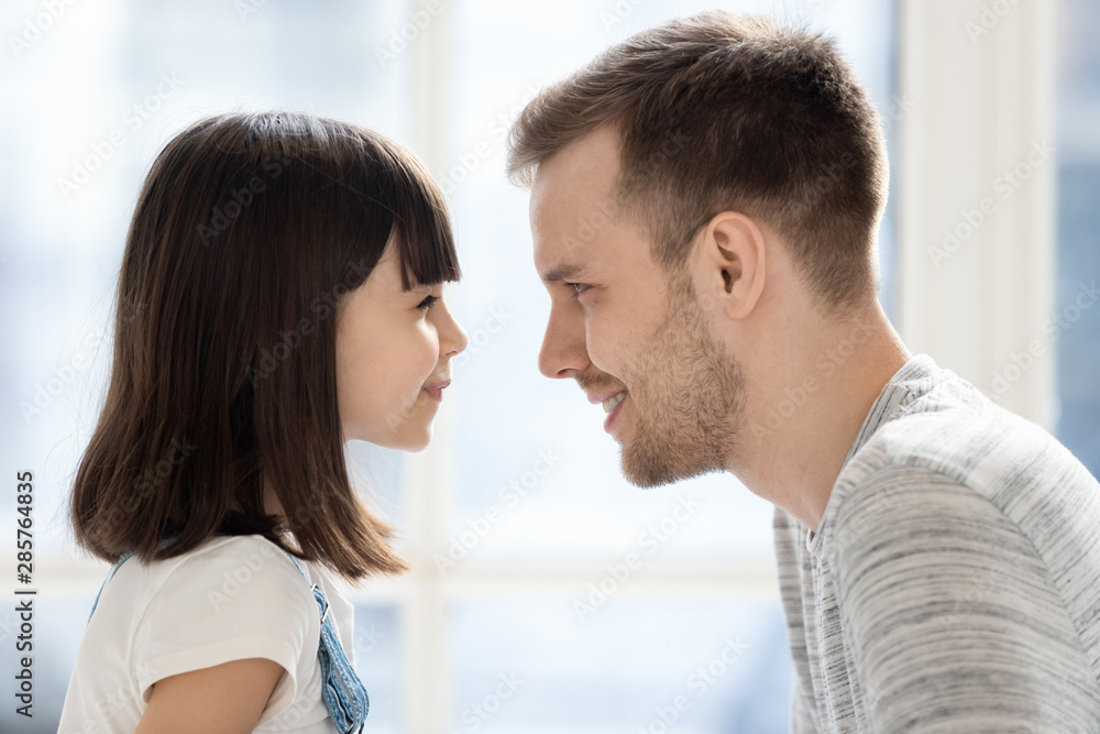 Fototapeta premium Cute little child daughter make funny face looking at dad