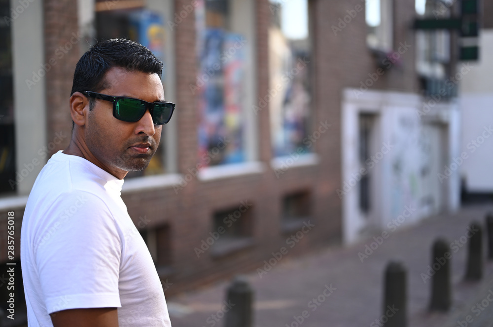 Confident and fashionable dark man wearing sunglasses and walking in a urban area Confident and fashionable dark man wearing sunglasses and walking in a urban area