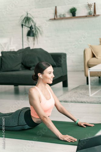 Happy woman exercising at home near tablet stock photo