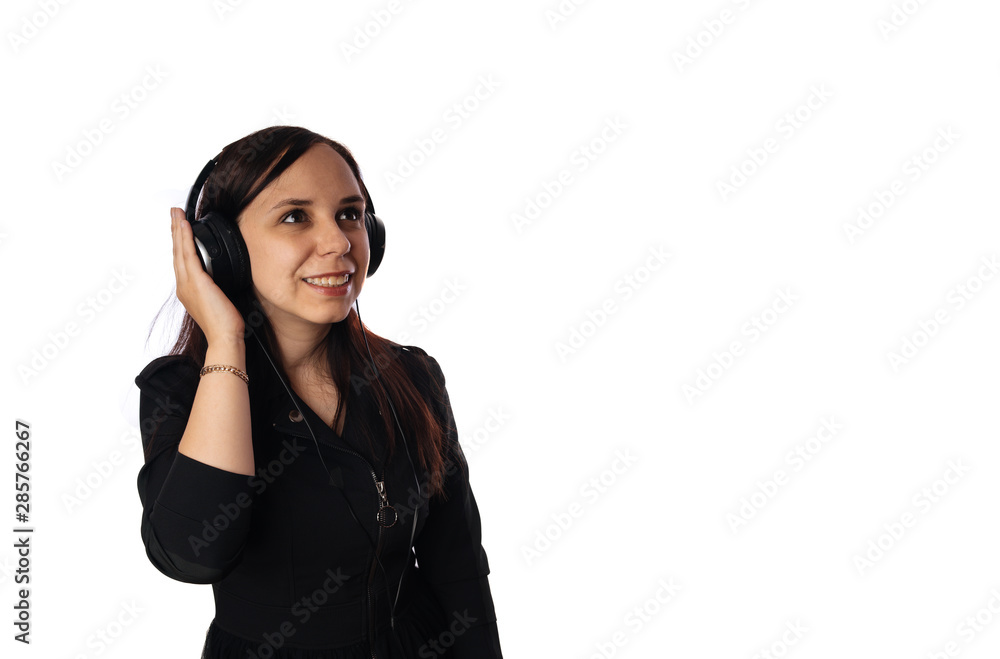 A beautiful young woman in headphones is dancing isolated on white background. The concept of International Music Day. A beautiful young woman in headphones is dancing isolated on white background. The concept of International Music Day.