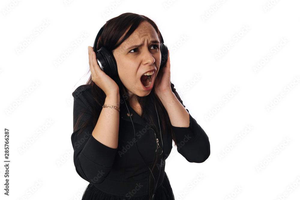 A beautiful young woman in headphones is dancing isolated on white background. The concept of International Music Day. A beautiful young woman in headphones is dancing isolated on white background. The concept of International Music Day.